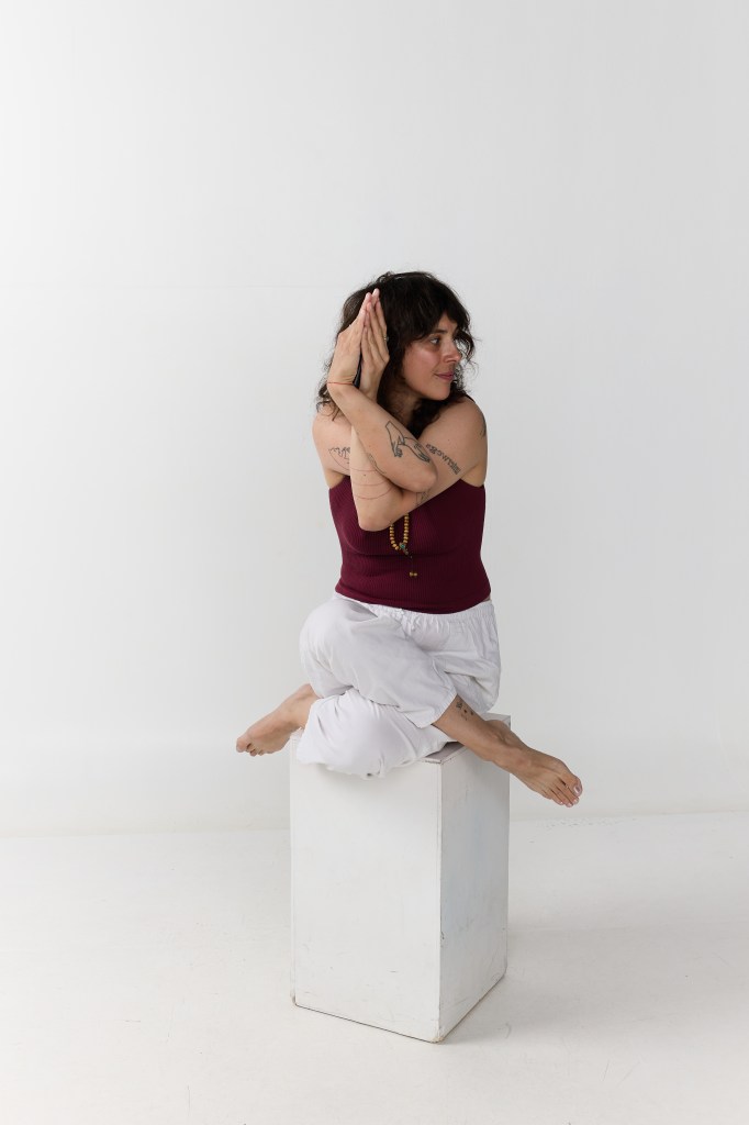 posture de l'aigle, assise sur un cube blanc sur fond blanc